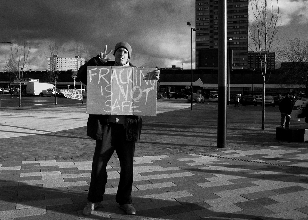 a demonstrator holding a sign against fracking