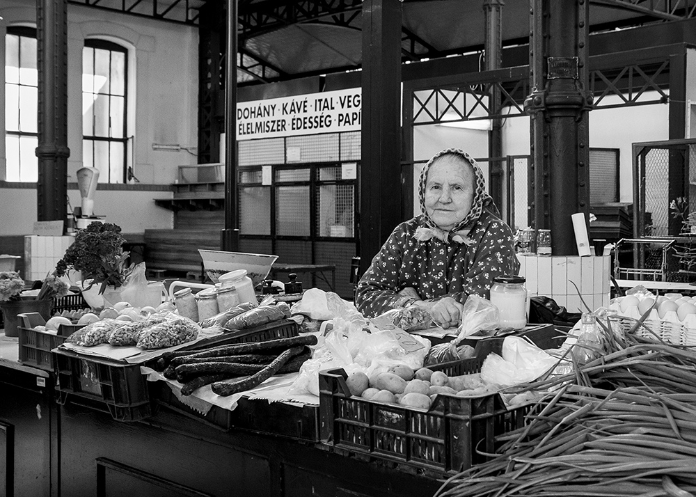 an elderly lady selling groceries at a market