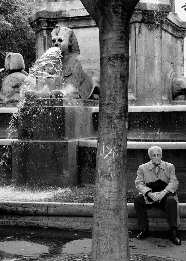 a man sitting in front of a fountain