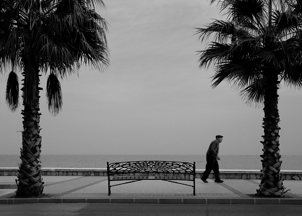 an elderly man walking the beach boulevard in Spain