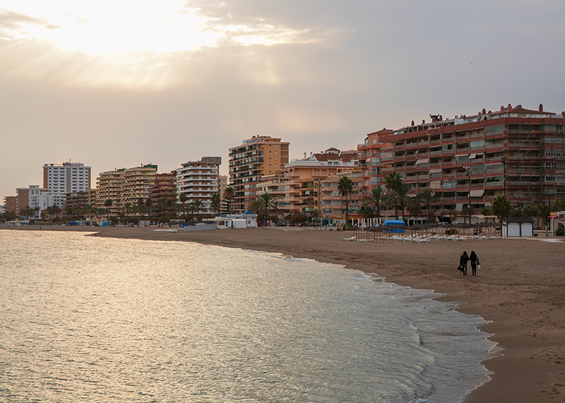 a couple walking on a beach at costa del sol in a sun set